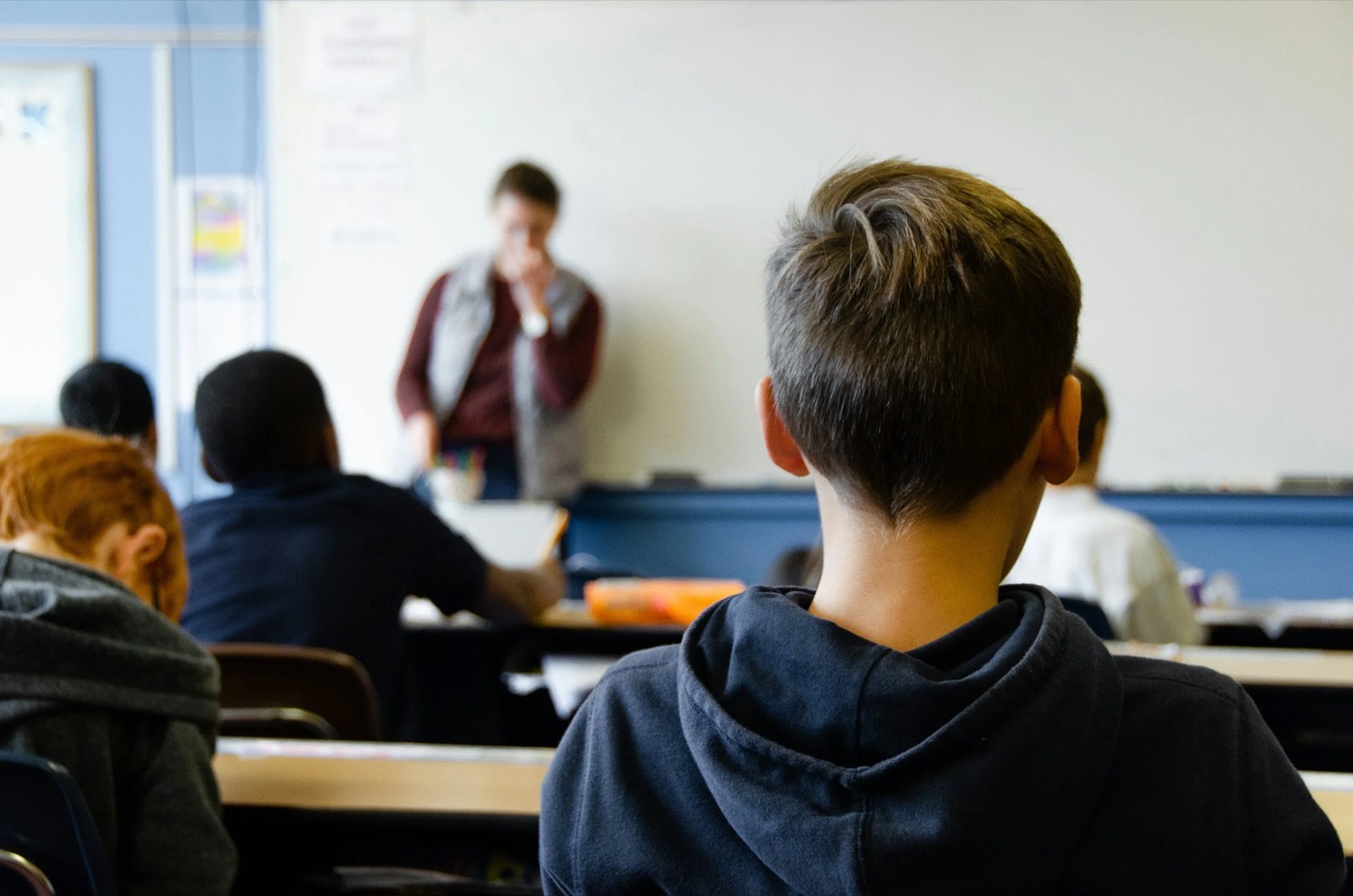 A classroom with students and a teacher at the whiteboard